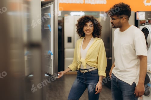 Preview: Couple Examining Appliances in Modern Electronics Store with Happy Expressions
