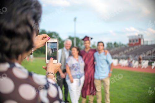 Preview: Mature woman taking family portrait at graduation ceremony