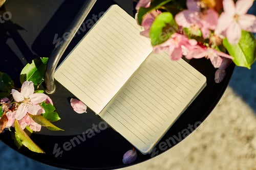 Preview: Open notebook and flowers and on the small black table on terrace