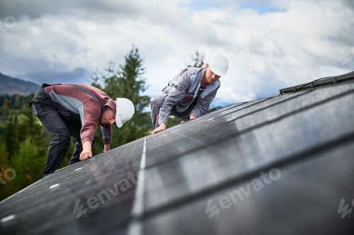 Preview: Technicians installing photovoltaic solar panels on roof of house.