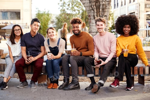 Vista previa: Six trendy millennial friends sitting on a wall by a fountain, drinking cold brews smiling to camera