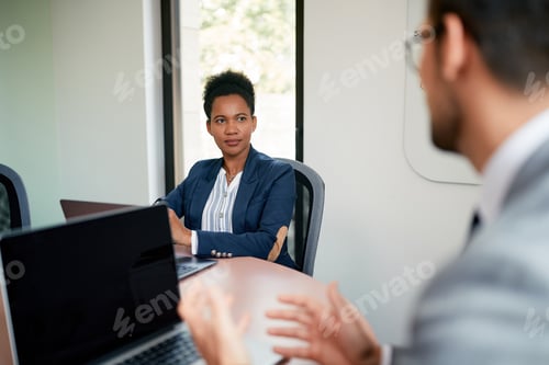 Preview: Black CEO talking to her colleague during business meeting in the office.