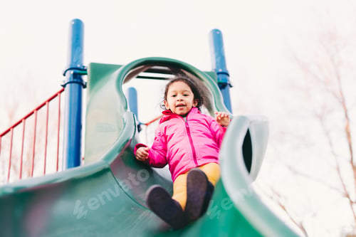 Preview: Cute toddler girl outdoors at playground park playing and having fun