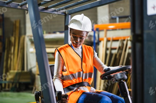 Preview: Female worker operating forklift in lumberyard warehouse