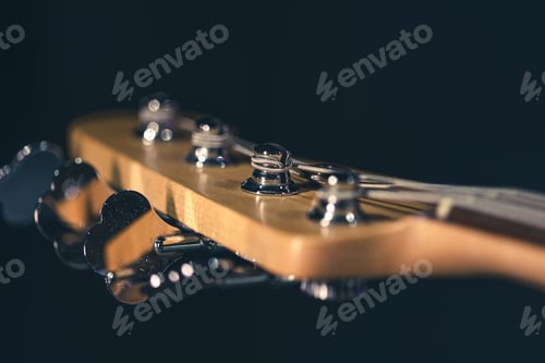 Preview: Close-up of a bass guitar fretboard on a blurred dark background.