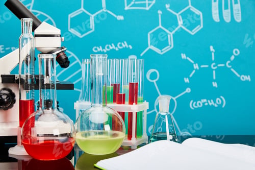 Preview: microscope, glass test tubes and flasks with colorful liquid near open copybook on blue background