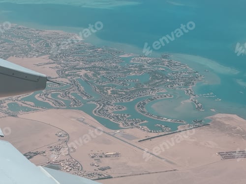 Preview: Airplane wing flying over tropical coastline resort city and desert airstrip