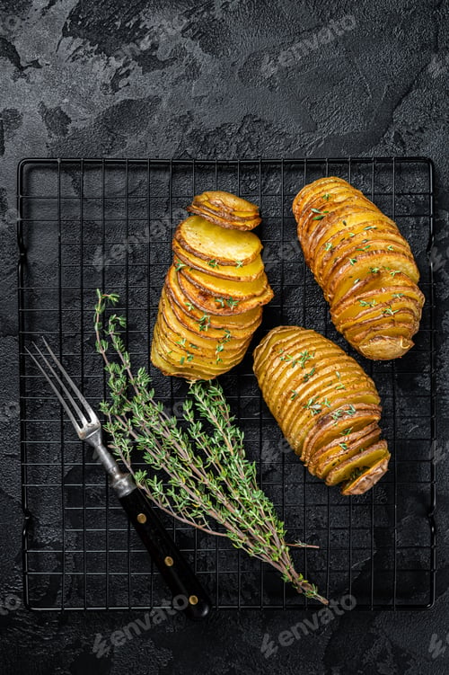 Preview: American traditional Homemade Hasselback Potato with Fresh Herbs. Black background. Top view