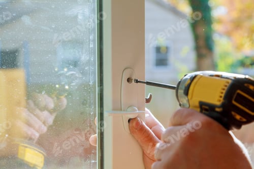 Preview: Handyman using a drill to installing lock in door in a house