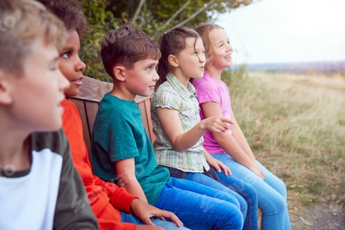 Preview: Group Of Children At Outdoor Activity Camp Resting On Bench During Walk Through Countryside