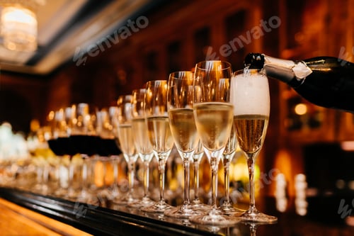 Preview: Row of glasses filled with champagne and other beverages, someone holds bottle