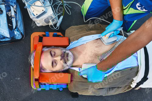 Preview: Ambulance paramedic using defibrillator performing cardiopulmonary resuscitation on casualty. First