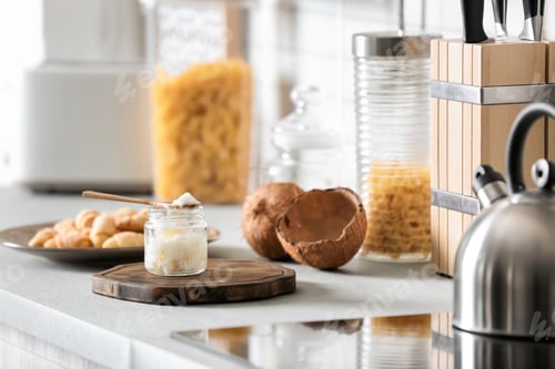 Preview: Jar with coconut oil on table in kitchen. Healthy cooking