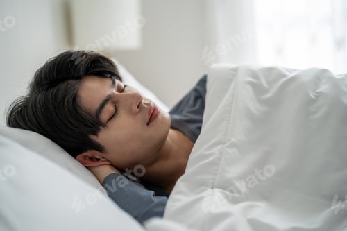Preview: Asian handsome man lying down on bed in bedroom in morning at home.