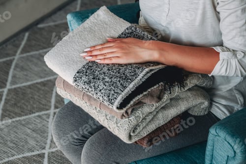 Preview: Female hands hold a stack of warm knitted sweaters