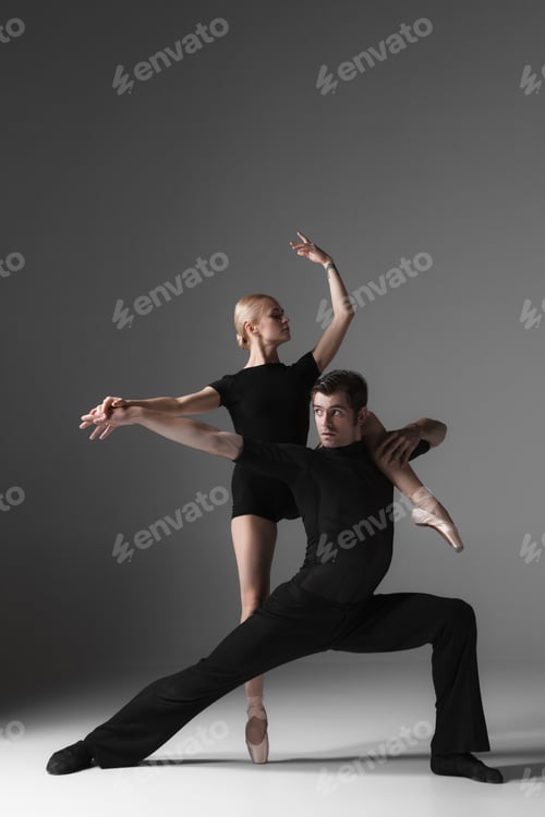 Preview: The Two Young Modern Ballet Dancers In Black Suits Posing Over Gray Studio Background