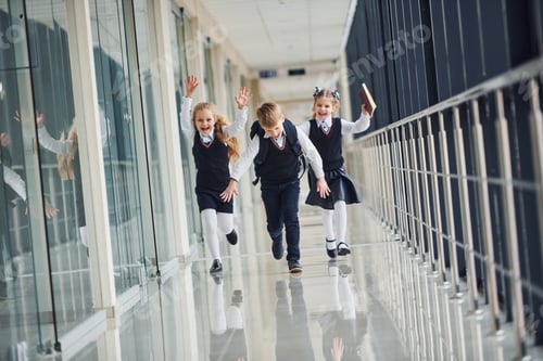 Preview: Active school kids in uniform running together in corridor. Conception of education