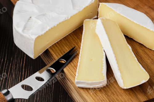 Preview: Close up of camembert or brie cheese on wooden cutting board