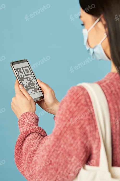 Preview: Lady wearing face mask and using smartphone in studio