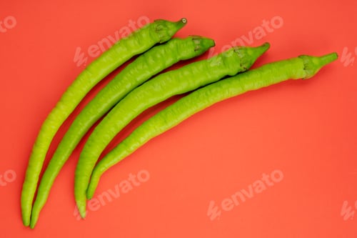 Preview: top view of green chili peppers isolated on red background