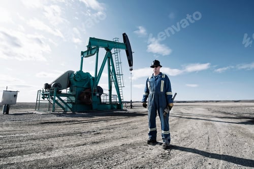 Preview: A man in overalls and a hard hat with a large wrench working at an oil extraction site.