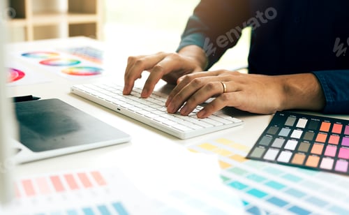 Preview: Graphic designer typing keyboard on desk in modern office.