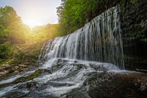 Preview: Waterfall surrounded by moss, trees, and stones in Ystradfellte Neath UK