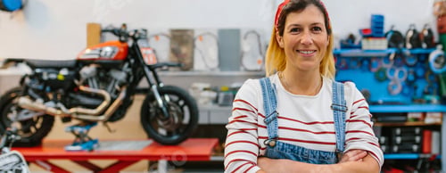 Preview: Portrait of mechanic woman standing on motorcycle factory