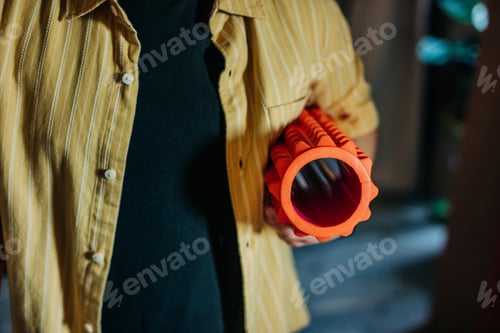 Preview: white European man in a yellow shirt is holding a ribbed conical massager at home