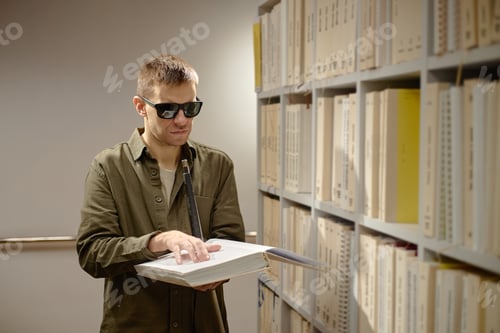 Preview: Young Adult Man Reading Braille Book Independently in Library