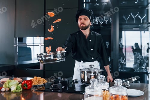Preview: Professional young chef cook in uniform frying food on the kitchen