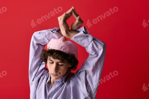 Preview: Stylish young man posing gracefully against a vibrant red backdrop