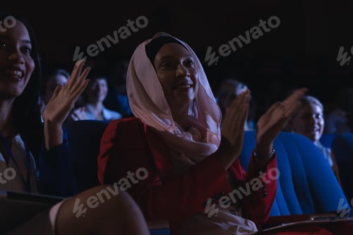 Preview: Low angle view of mixed race businesswoman sitting and clapping in the auditorium