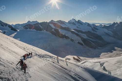 Preview: Mountaineers ascending a snowy peak under a radiant sun.