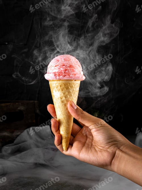 Preview: Woman's hand holding strawberry ice cream cone with smoke effect. Dark background.
