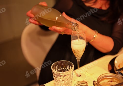 Preview: Midsection of woman pouring champagne in glass