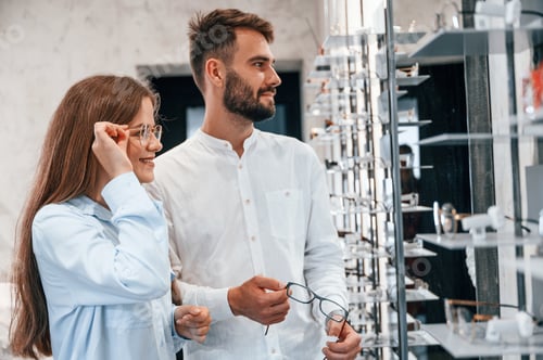 Preview: Helping to choose product. Man and woman in the glasses store