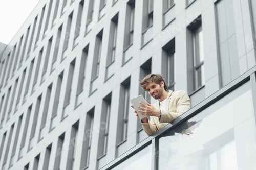 Preview: Man standing on balcony of office building with tablet