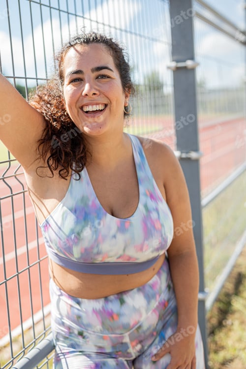 Preview: Portrait of a smiling sportswoman woman before going train on the athletics track outside the city