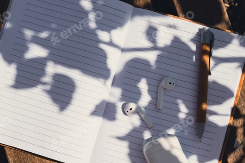 Preview: Paper notebook with wireless headphones. Mockup Coffee break. Audio healing, sound therapy wellness