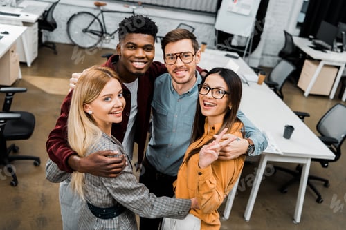 Preview: high angle view of multiethnic happy business colleagues looking at camera in office