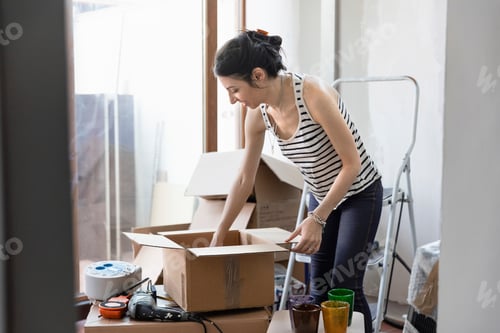 Preview: Woman unpacking a box in a sunny room during a move