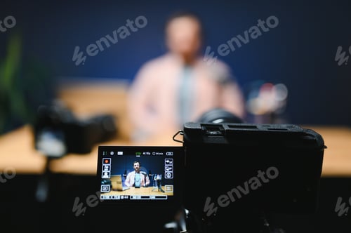 Preview: Man podcaster influencer blogger smiling while broadcasting his live audio podcast in studio