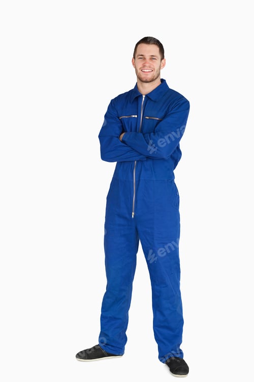 Preview: Smiling Young Mechanic In Boiler Suit With Arms Folded Against A White Background