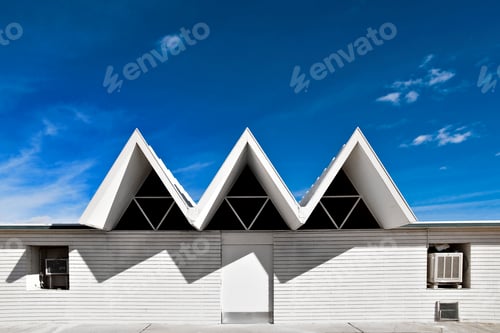 Preview: 49653,A building with three apexes in a row on the roof, and shadows on the white wall below.