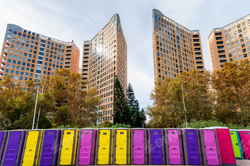 Preview: Row of portable chemical toilets of various colors placed for an event on the streets of the city.