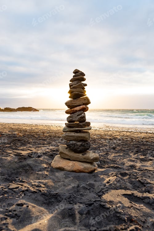 Preview: Stack of Stones Balance on a Beach Against a Cloudy Sky at Sunset Time.Zen Concept.Vertical Image