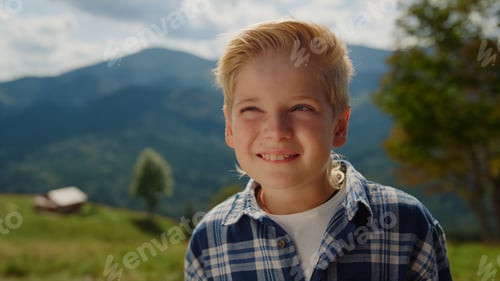 Preview: Portrait happy boy looking camera on mountains. Little man standing on meadow.