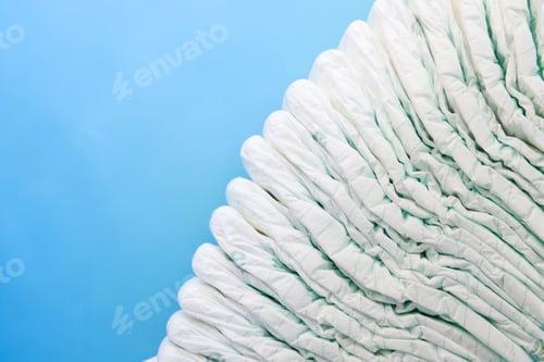 Preview: stack of baby diaper on blue background with copy space