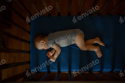Preview: The baby sleeps in a crib on a blue sheet